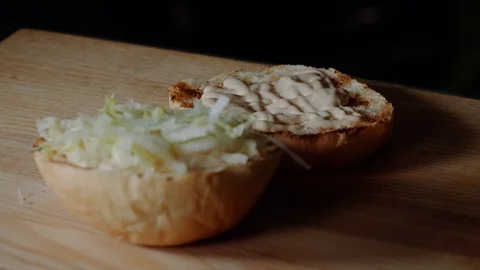 Chef making burger. frying the bun on the grill, putting sliced pickled cucumber Stock Footage 99363287