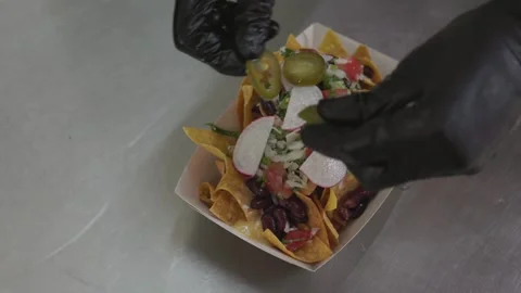 Chef making Mexican nachos adding pepper toppings over chips, close-up Stock Footage 246237500