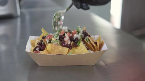 Chef making nachos adding toppings on traditional Mexican chips Stock Footage 246237642