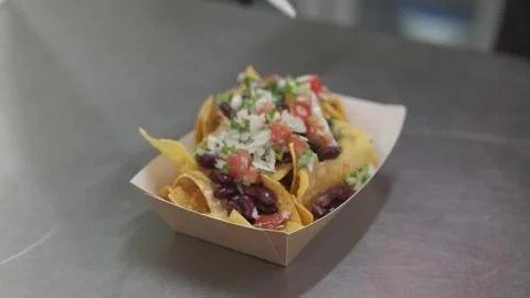 Chef making nachos adding vegetable toppings on traditional Mexican appetizer Stock Photos