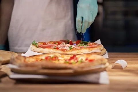 Chef making a parma or prosciutto ham Italian pizza in a close up view of his Stock Photos