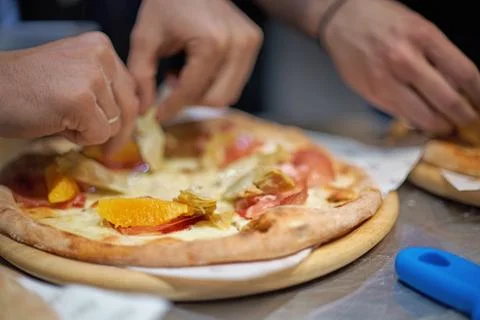 Chef making a parma or prosciutto ham Italian pizza in a close up view of his Stock Photos