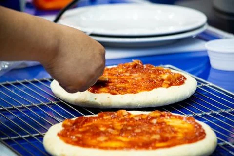 Chef making pizza at kitchen, Chef spreading cheese toppings on pizza base Stock Photos