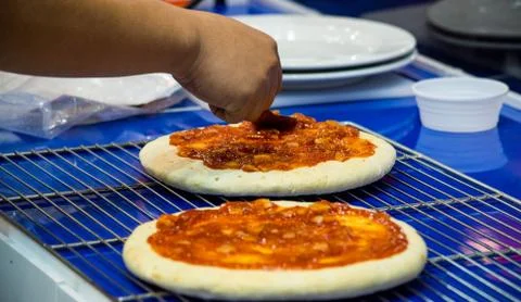 Chef making pizza at kitchen, Chef spreading cheese toppings on pizza base Stock Photos