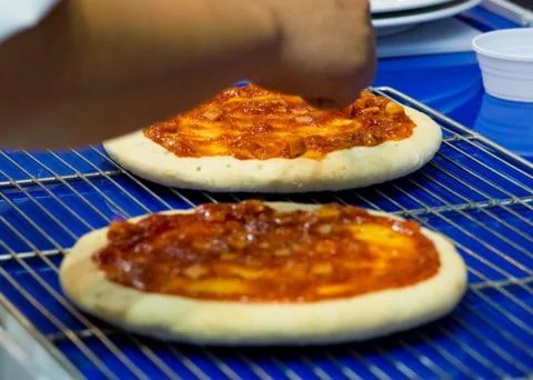 Chef making pizza at kitchen, Chef spreading cheese toppings on pizza base Stock Photos