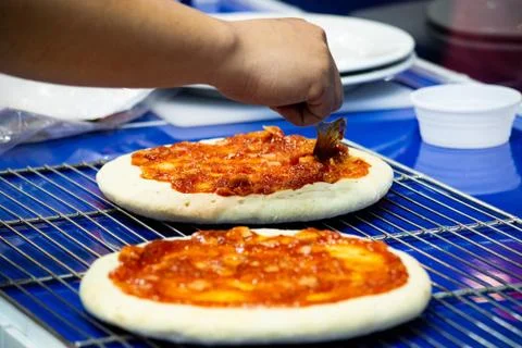 Chef making pizza at kitchen, Chef spreading cheese toppings on pizza base Stock Photos