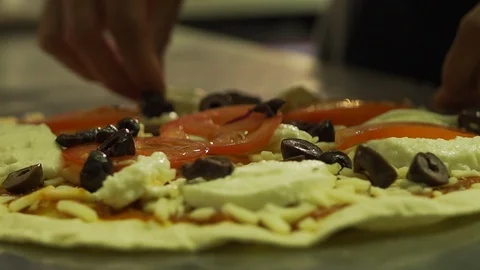 Chef making pizza puts olives onto pizza in professional restaurant kitchen Stock Footage 101646917