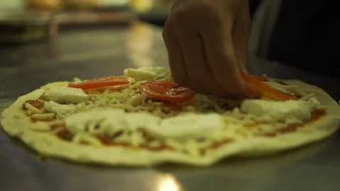 Chef making pizza in restaurant kitchen, putting tomato onto pizza Stock Footage 101646830