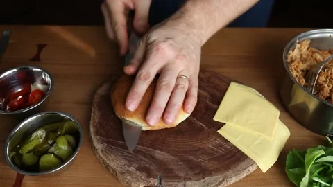 Chef making a pulled pork sandwich on a fresh roll. Cuts a bun to loads meat Stock Footage 147219294
