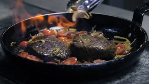 Chef making steak in flambe style on a pan. Oil and alcohol fire with open Stock-Footage 141507940