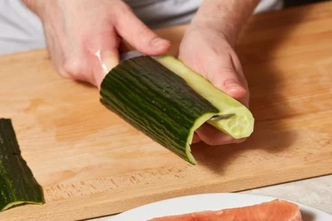Chef making sushi rolls. Cutting cucumber Stock Photos