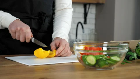 Chef man in black apron sliced fresh yellow pepper on board in home kitchen Stock Footage 150279096