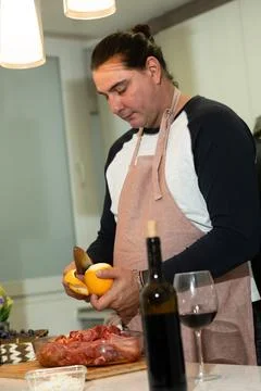 Chef man peeling an orange preparing meat for a meal Foto stock