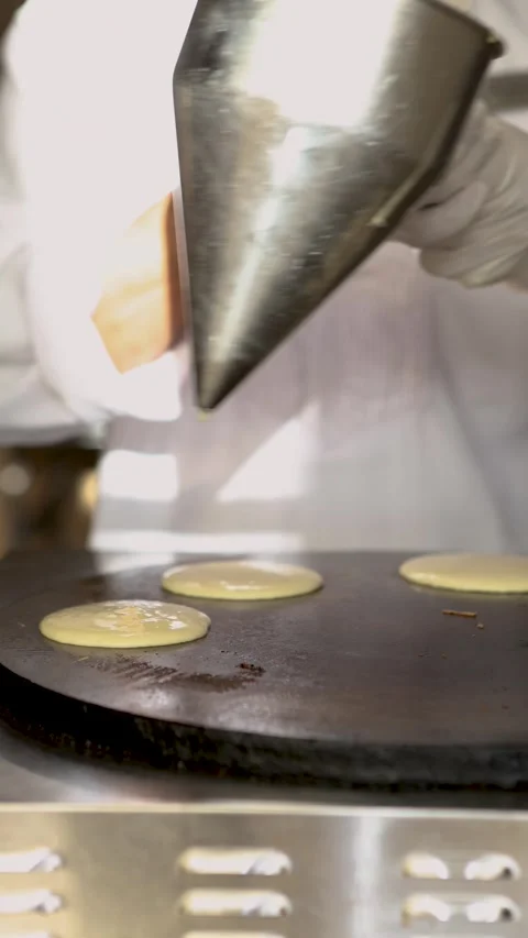 Chef man preparing small round pancakes on hot surface for delicious breakfast Stock Footage 316222372