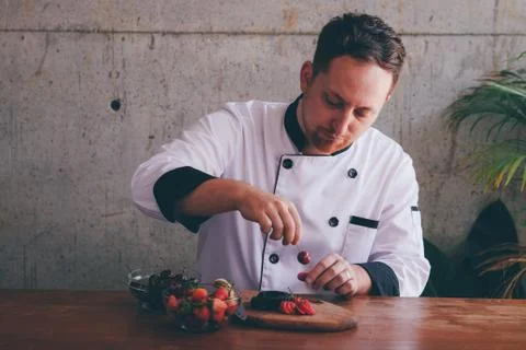 Chef man put cherry to the cake decorating food. Fotos Stock