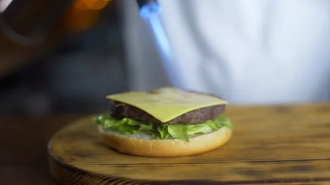 Chef melts cheese with help of gas burner on the cutlet in process of making  Stock Footage 143778869