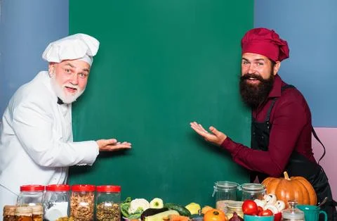 Chef men in cook hat pointing spoon on blank board menu. Stock Photos
