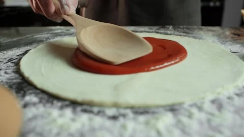 Chef men spreads tomato paste on pizza dough in the kitchen table Stock Footage 105418108