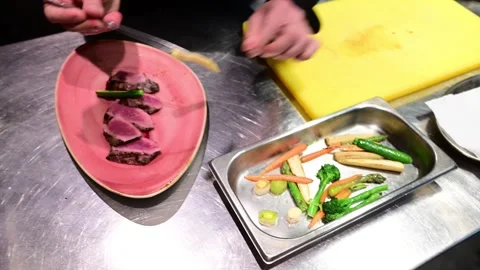 Chef meticulously plating a rare meat fillet with vegetables Video stock 327580139