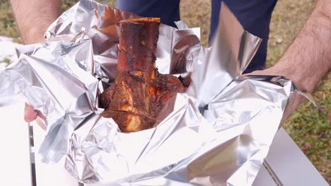 The chef meticulously wraps the succulent meat in foil, ensuring it's ready for Video stock 273124154