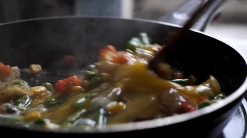 The chef mixes chicken eggs with vegetables in a frying pan Stock Footage 263750217
