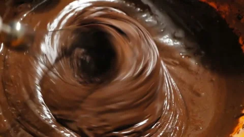 The chef mixes the chocolate with a blender, preparing the ingredients for the Stock Footage 153484087