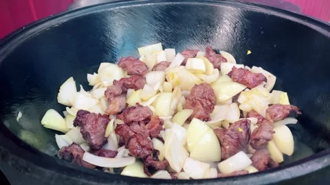 The chef mixes the meat and vegetables in a large pot with a slotted spoon. Stock Footage 278601032