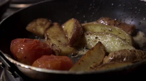 A Chef mixes tomatoes, potatoes and mushrooms in a hot pan Stock Footage 61559996