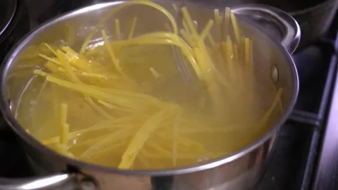 Chef mixing boiling spaghetti with fork in kitchen Stock Footage 297464644