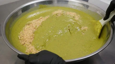 Chef mixing creamy pistachio paste with crunchy kataifi pastry for viral Dubai c Stock Footage 337751623