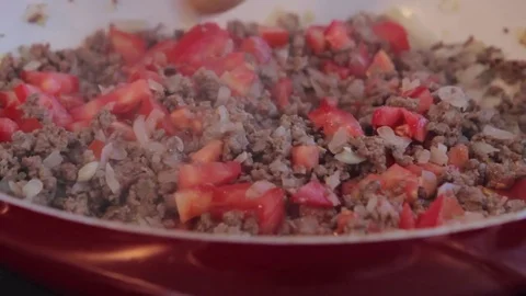Chef mixing frying ground meat with sliced onions and tomatoes on ceramic pan.  Stock-Footage 71123373