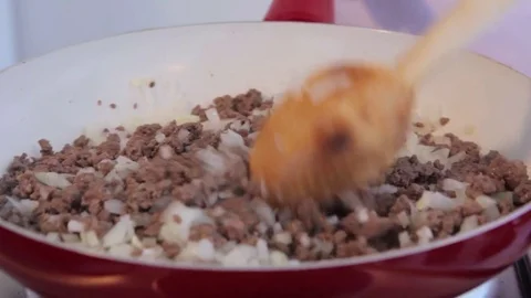 Chef mixing frying ground meat with sliced onions on ceramic pan.  Stock-Footage 71123748