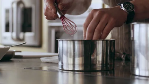 Chef mixing ingredients in a steaming pot on a stovetop in interior kitchen with Stock Footage 199457136