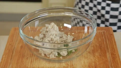 A chef mixing minced fish with egg and chopped fresh herbs in a glass bowl to pr Stock Footage 340553109
