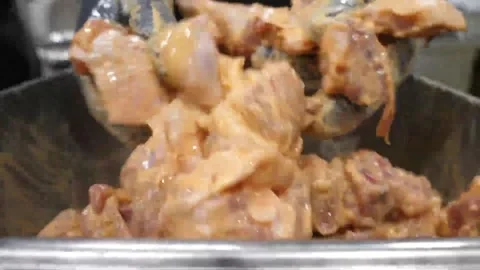 Chef mixing raw chicken pieces in spicy orange marinade for Korean fried chicken Video stock 343028743