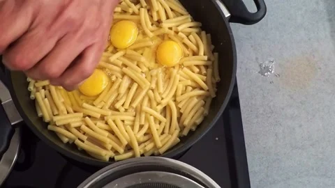 Chef mixing raw eggs with cooked pasta in a pan Stock Footage 322060234