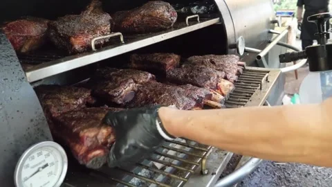 Chef Opening Lid of Professional Offset Smoker to Reveal Rows of Juicy Smoked Be Stock Footage 338212442