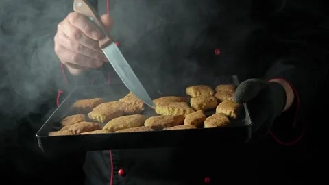 Chef or baker in black uniform holds a tray of freshly baked cookies, preparing Stock Footage 333924854