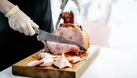 Chef or caterer slicing ham for cooking, catering, party, or meal time Foto stock