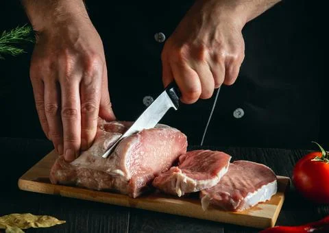 Chef or cook cutting meat with knife on kitchen, cooking food. Stock Photos
