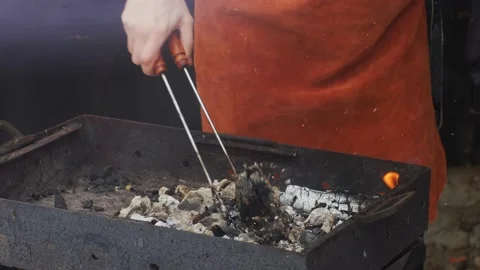 Chef or cook preparing outdoor coal fire grill with pliers Stock Footage 146791860