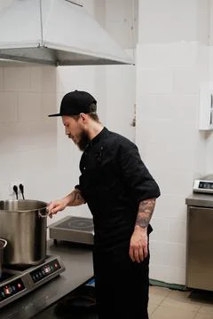 Chef at the oven, preparing big pot for making broth Stock Photos