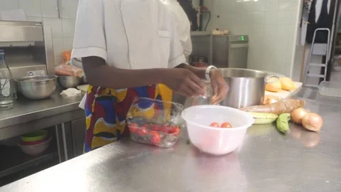 Chef in a patterned apron sorts fresh cherry tomatoes into a prep bowl for a Stock Footage 325481128