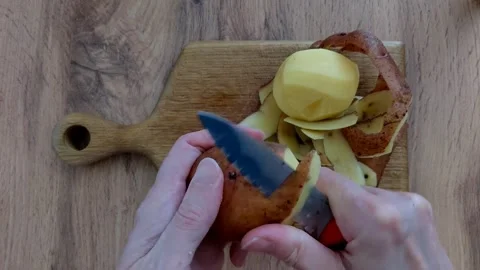 Chef peel a raw potato with a sharp knife with a black and red handle Stock Footage 336632311