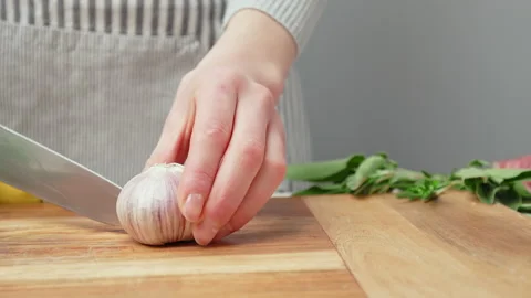 Chef peeling garlic close-up and taking off the skin then slicing in half in 4K. Stock Footage 145997546