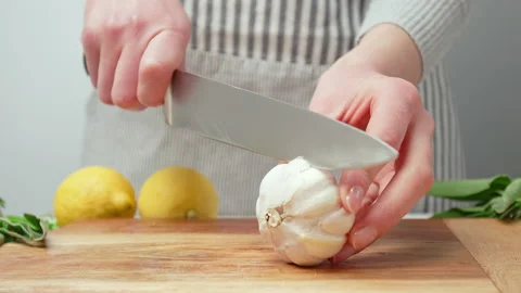 Chef peeling garlic close-up and taking off the skin then slicing in half in 4K. Stock Footage 145997626