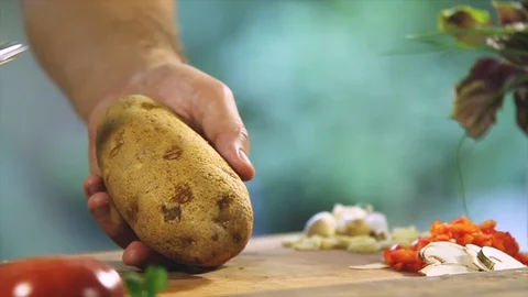 Chef peeling a potato in a kitchen lit by sunlight Stock Footage 100615329