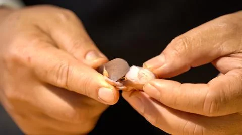 A chef is peeling shallots with a small sharp kitchen knife for preparing t.. Stock Photos