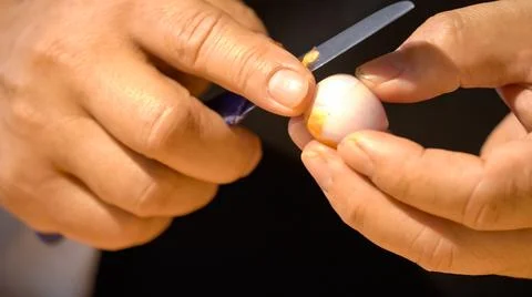 A chef is peeling shallots with a small sharp kitchen knife for preparing t.. Foto stock