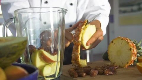 Chef peeling the skin off a pineapple with knife on chopping board Stock Footage 85814746